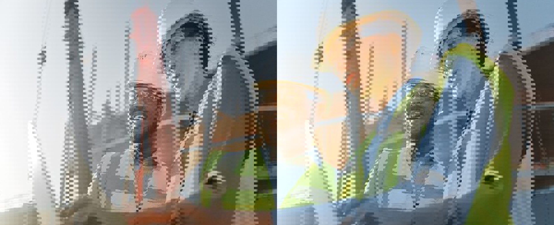 Two people in hardhats on site looking at a laptop